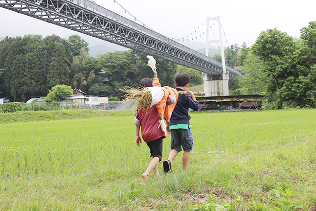 川場村の大自然の中、手づくりのかかしを運ぶ子どもたち